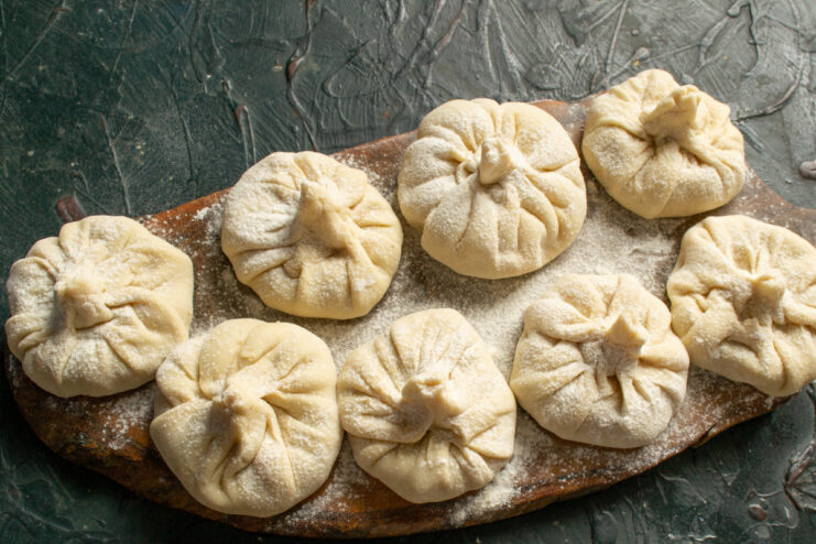 Raw khinkali dusted with flour on a cutting board