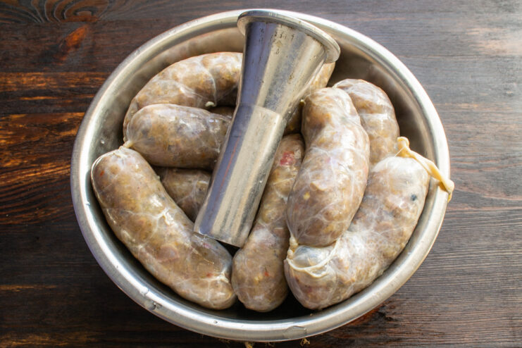 Methods for stuffing sausages Raw sausages next to a metal stuffing attachment
