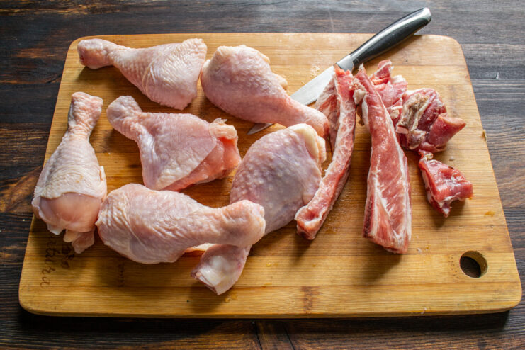 Broth Ingredients Raw chicken drumsticks and cut pork ribs on a cutting board