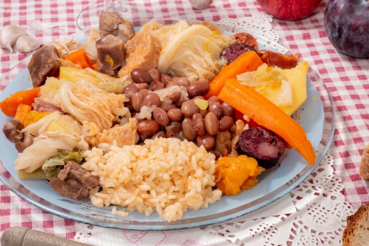 Large plate of Cozido à Portuguesa with boiled meats, smoked sausages, beans, and rice