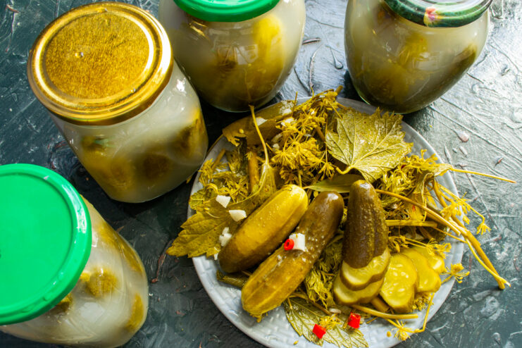 Sliced fermented pickles on a plate next to storage jars