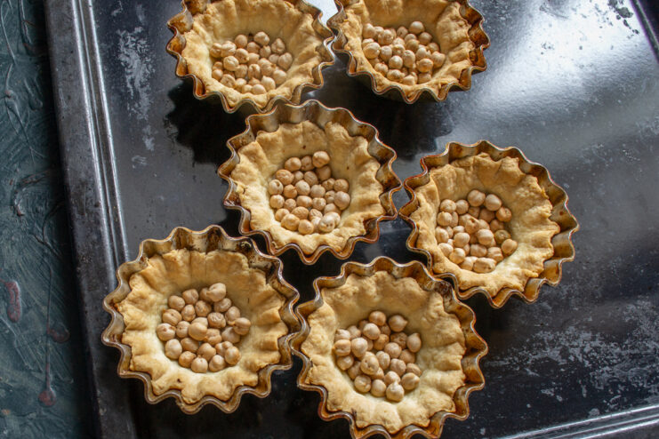 Blind Baking Tartlet Shells Tartlet shells filled with chickpeas on a baking sheet