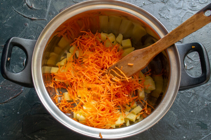 Adding Carrots Grated carrots layered over diced potatoes in a pot