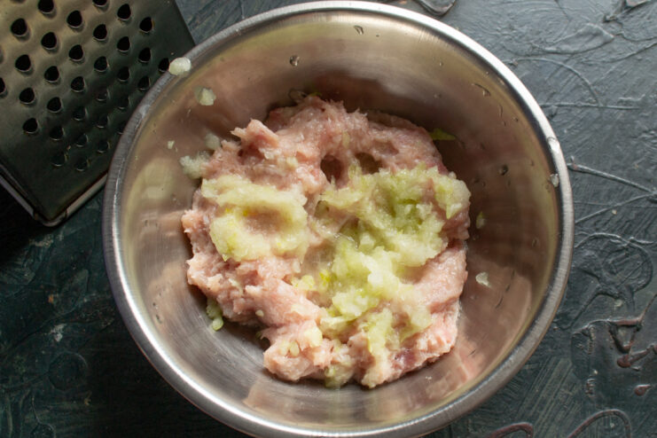 Adding onion to the mince Coarsely grated onion mixed into the minced meat
