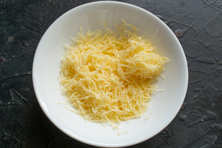 Preparing the Cheese Grated cheese in a white bowl for the filling