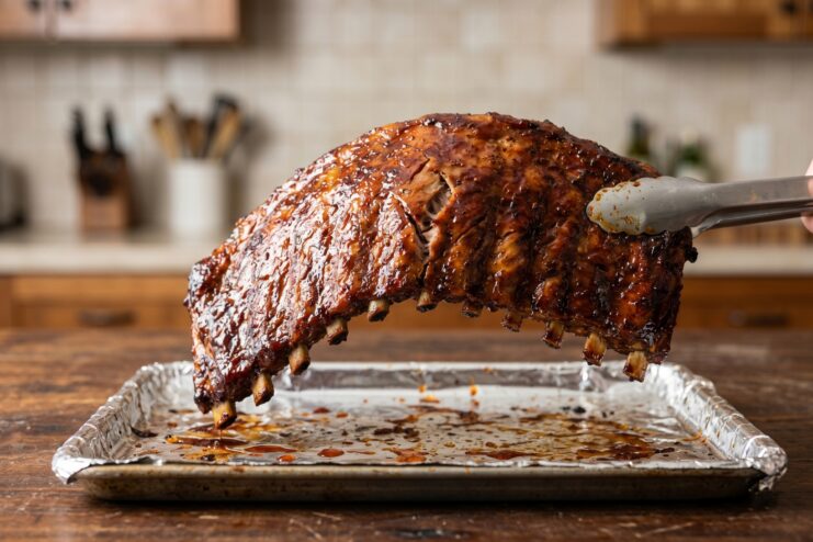 Testing Meat Doneness Testing pork ribs for doneness by lifting the rack with metal tongs