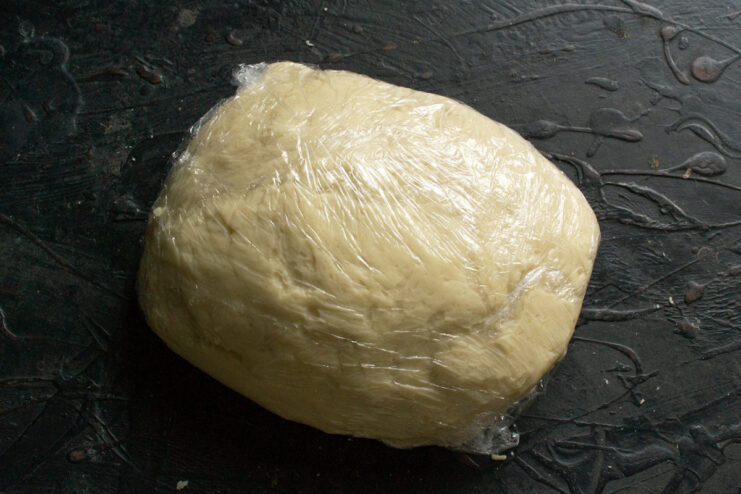 Resting the Dough Dough wrapped in plastic wrap resting on a counter