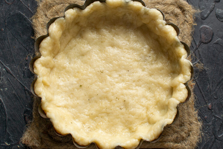 Shaping the pie crust Rolled pie dough pressed into a fluted tart pan.