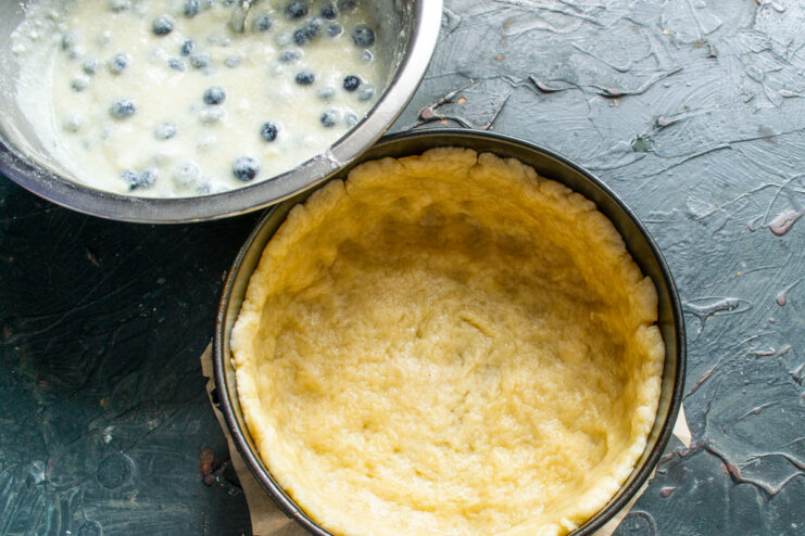Placing rolled dough into the baking pan Pie dough pressed into a springform pan with high edges