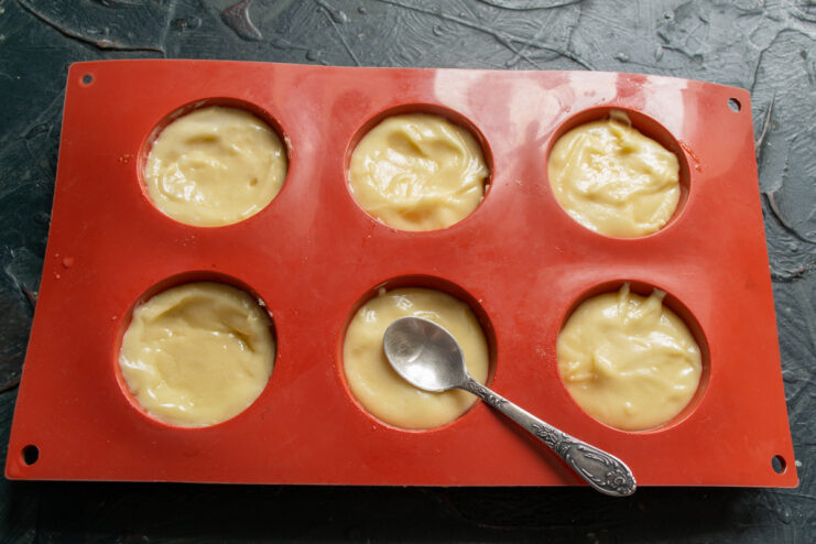 Portioning the Batter Spoonfuls of batter distributed into greased silicone molds