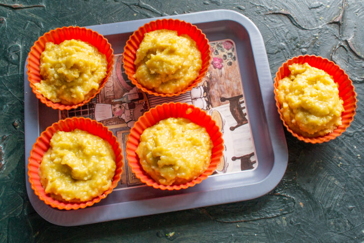 Cake batter portioned into bright orange silicone muffin molds