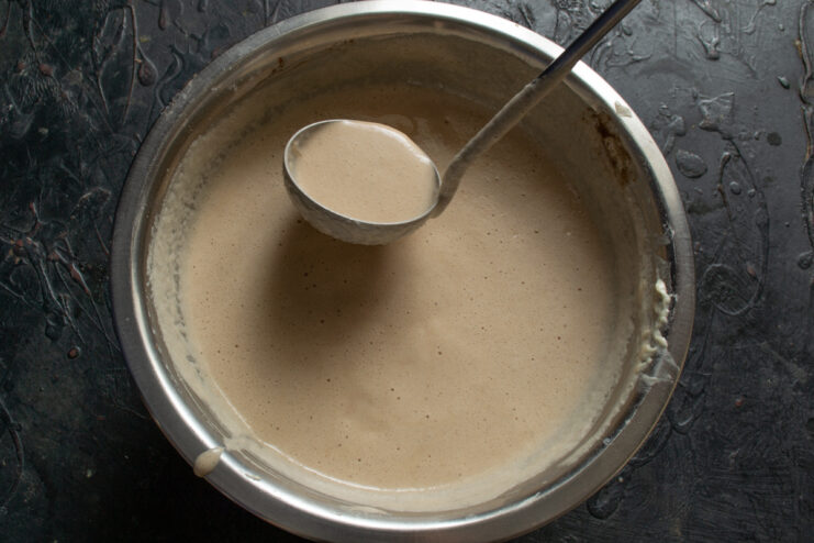 Measuring crepe batter with a ladle Scooping a small ladle of chocolate crepe batter for the skillet
