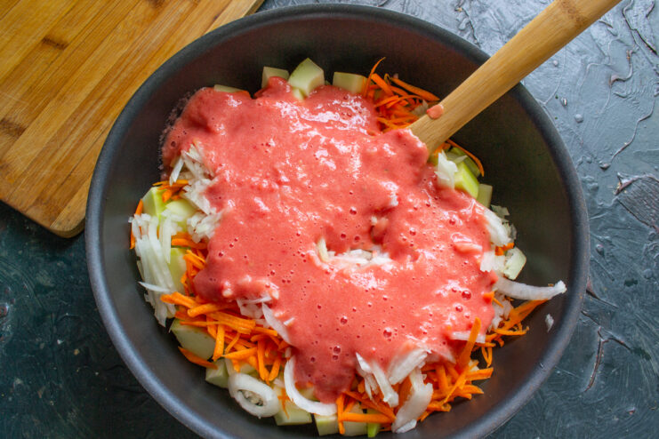 Tomato purée poured over vegetables in a pan