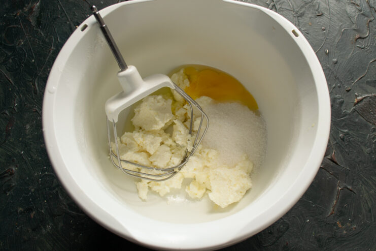Farmer's cheese, egg, and sugar combined in a mixing bowl