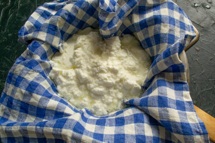 Transferring the curd into cheesecloth Cheese curd resting in a cheesecloth-lined colander to drain whey