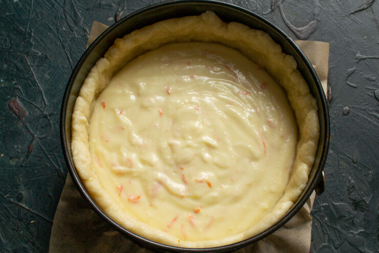 Cheese filling spread evenly inside the raw dough base in a pan