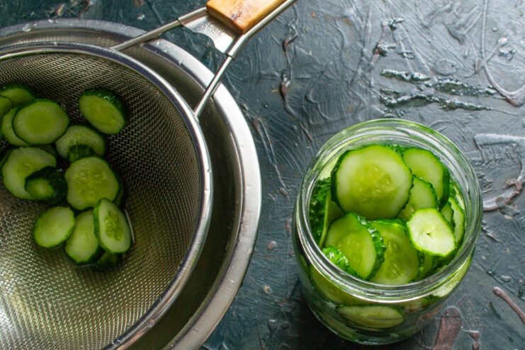 Packing Cucumbers into Jars Packing cucumber slices into a clean glass jar