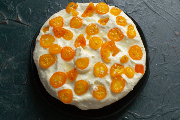 Final Cake Decoration Arranging candied kumquats on top of a frosted mascarpone cake