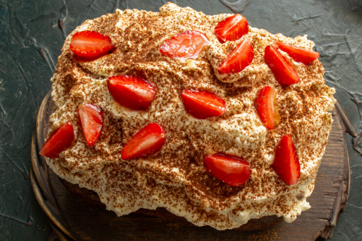 The final touch Arranging honey-glazed strawberry slices on top of the cake