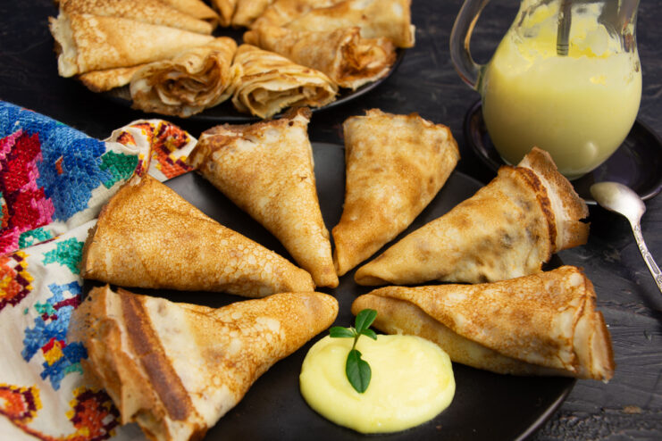 Stack of hot crepes generously drizzled with delicate homemade vanilla sauce