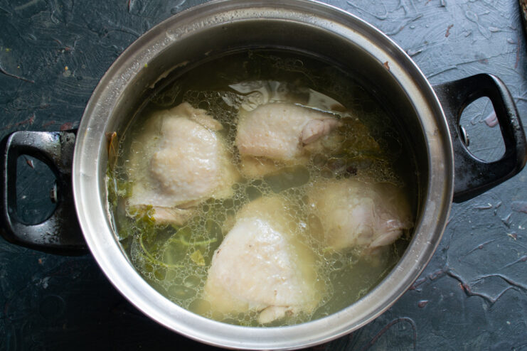 Simmering chicken in broth Cooked chicken resting in a pot of clear broth