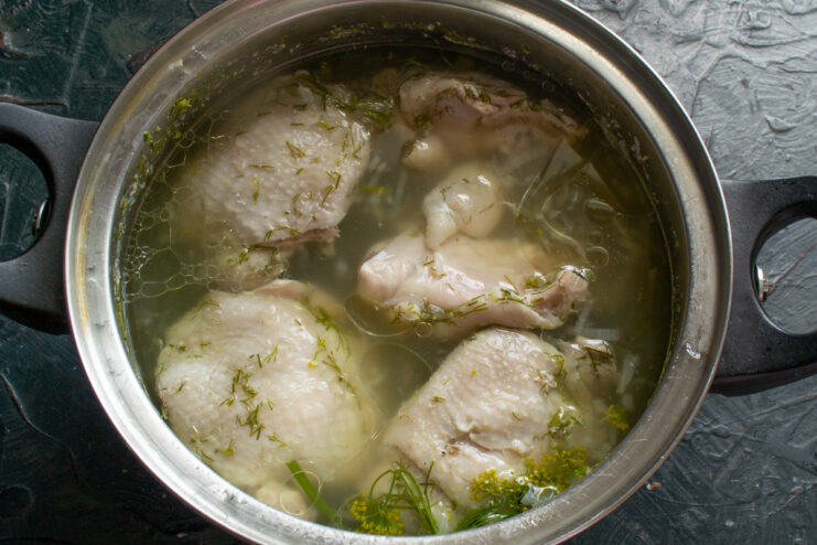 Boiling the chicken Boiled chicken simmering in clear broth inside a pot.