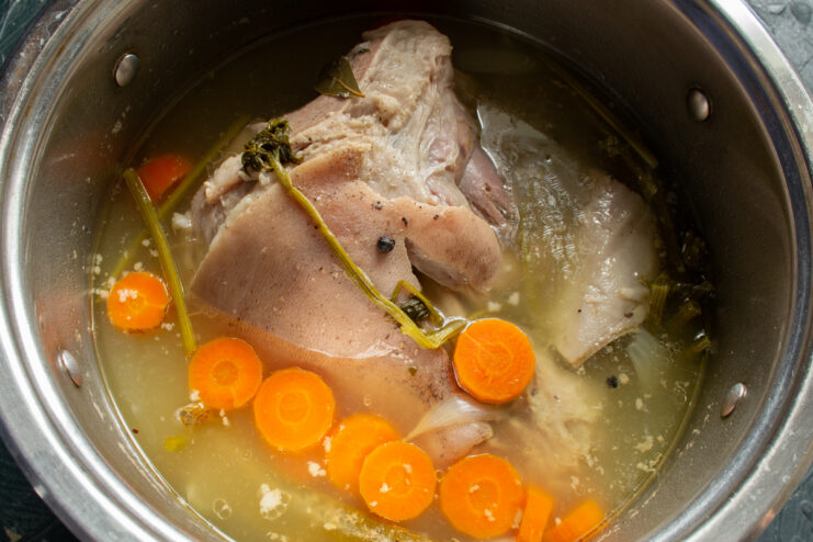Finished Broth Cooked pork hock in clear broth with carrots.