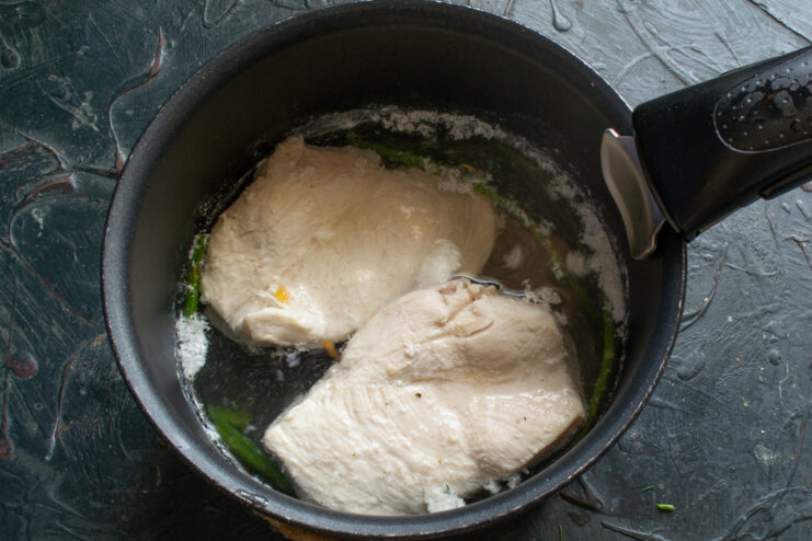 Cooked chicken breast Boiled chicken breast resting in a flavorful herb broth in a pot