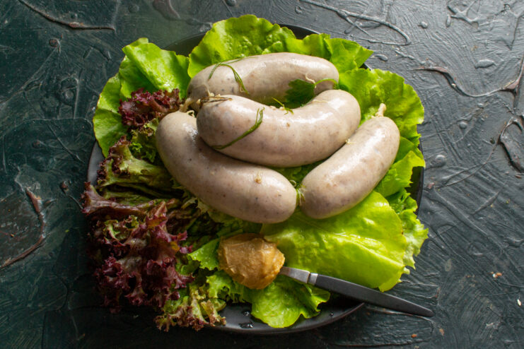 Serving the sausages Boiled sausages on a plate with lettuce leaves and mustard