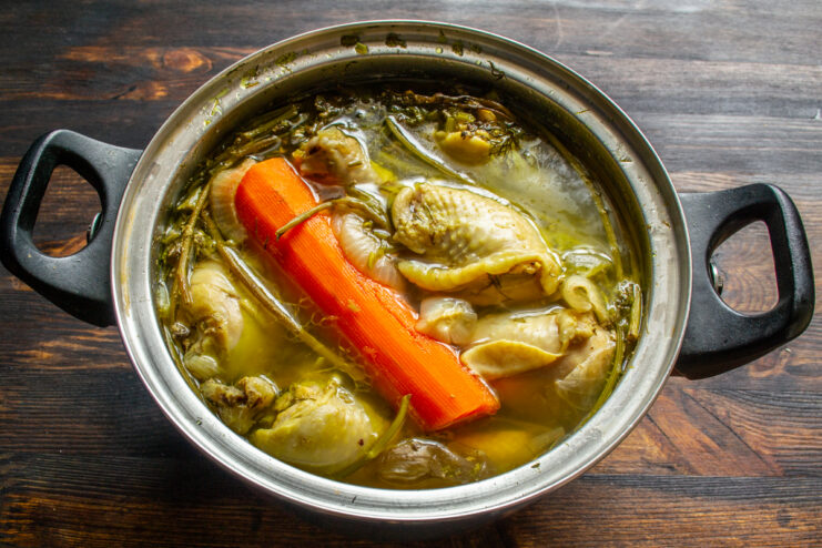 Simmering The Aspic Broth Simmering chicken broth with a whole carrot in a pot
