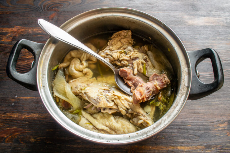Preparing the Meat Base Boiling chicken meat and gizzards with aromatics in a large pot