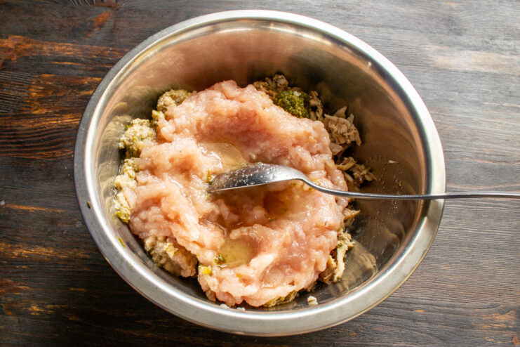 Mixing Broth Into Minced Meat Pouring gelatin broth into a mixing bowl filled with minced chicken