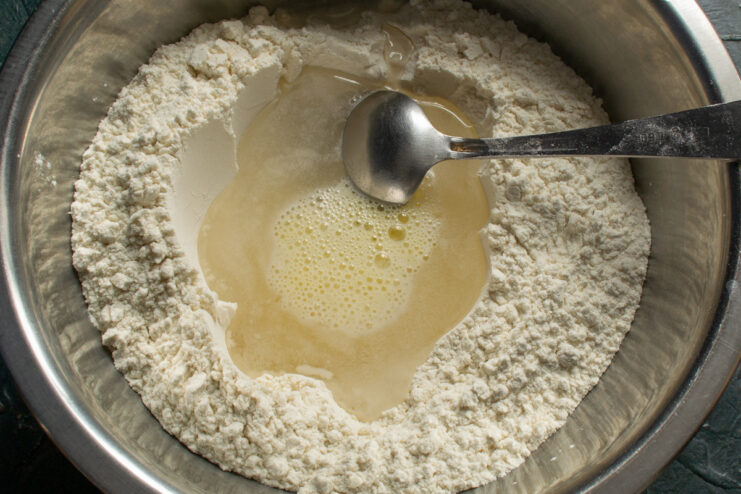 Pouring a beaten egg into the flour and water mixture