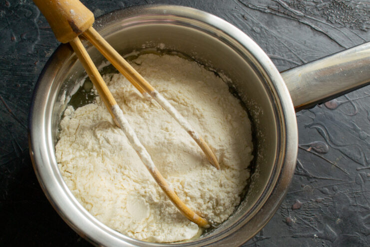 Adding flour into the hot liquid mixture in a saucepan