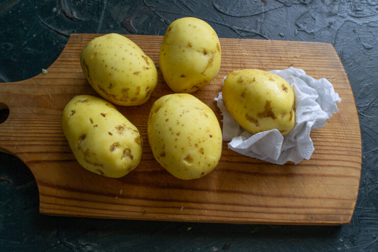 Preparing the potatoes Washing and drying raw potatoes on a cutting board