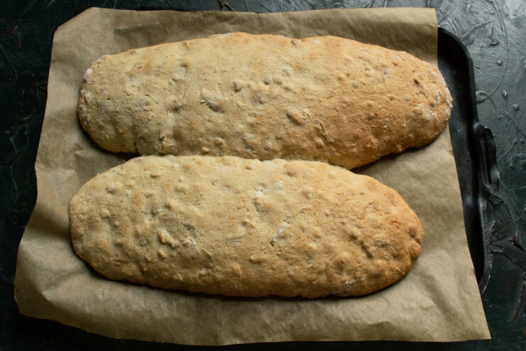 First bake Baked golden biscotti logs on parchment paper