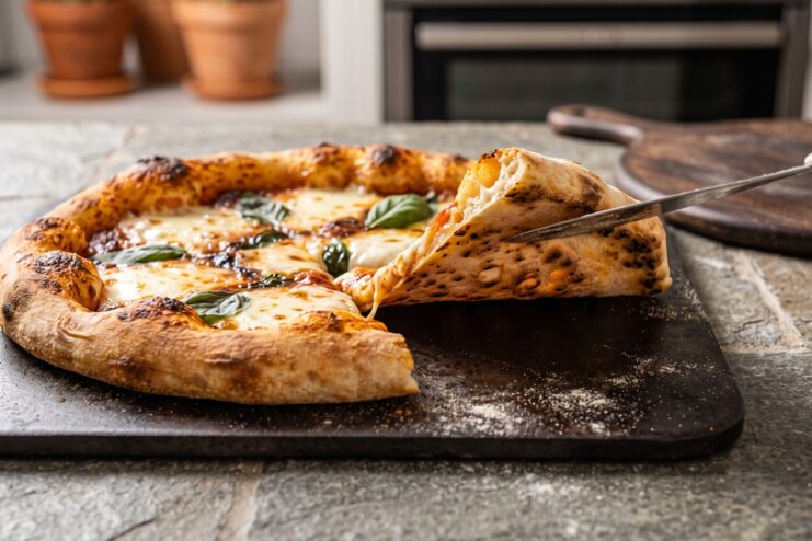 Baked Pizza on a Baking Stone in the Oven Baking homemade pizza in the oven on a baking stone with a crispy leopard-spotted crust.