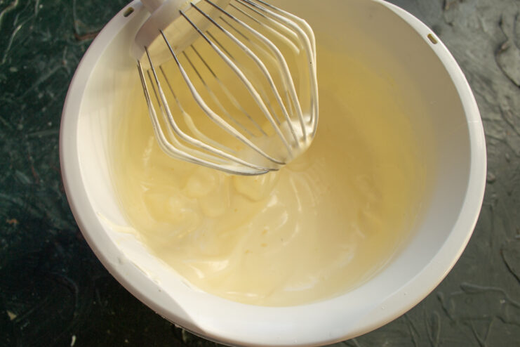 Whipping Eggs Until Fluffy Thick whipped egg and sugar mixture in a stand mixer bowl
