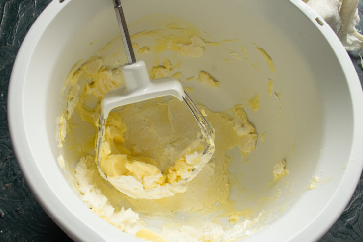 Preparing the creamy cheese base Whipped butter and sour cream inside a white mixer bowl