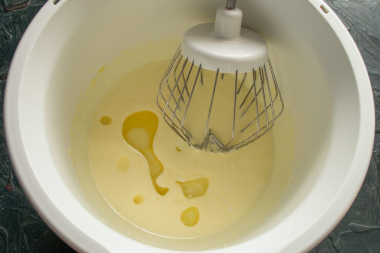Whipping eggs with sugar, milk, and oil for the Nochka pastry batter.