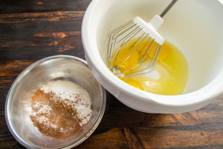 Prepping Cake Ingredients Eggs and sugar in a mixer bowl alongside a bowl of dry ingredients