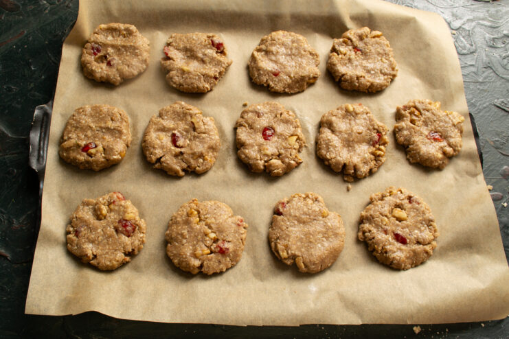 Shaping the cookies Formed oatmeal cookie dough balls arranged on a parchment-lined baking sheet