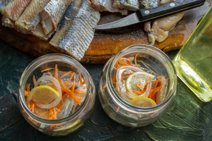 Pouring the vegetable oil Adding a tablespoon of neutral vegetable oil into a glass jar with herring