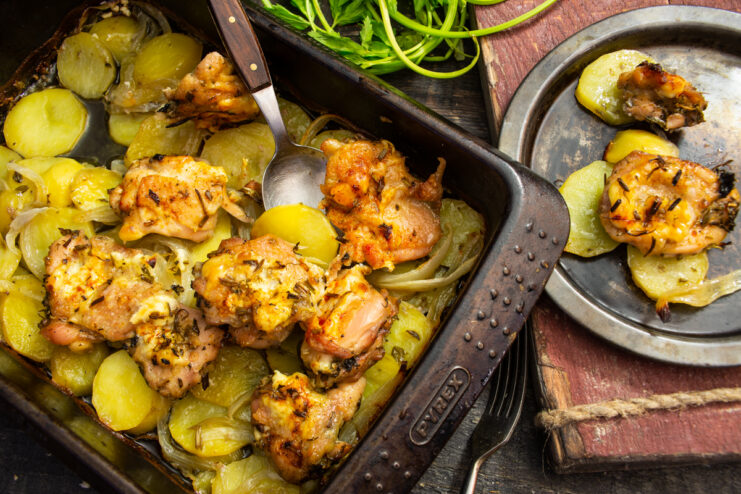 Roasted chicken with potatoes and fragrant herbs in a baking dish