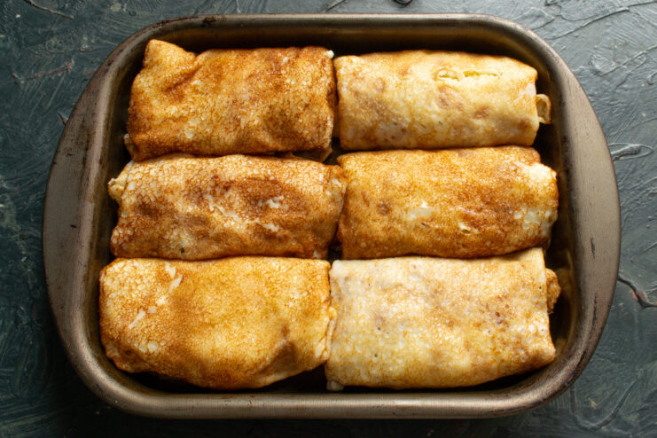 Baked Crepes From The Oven Baked stuffed crepes resting in a glass baking dish