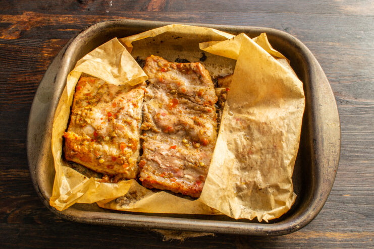 Checking the ribs after the first bake Baked pork ribs exposed in open parchment paper after the first hour in the oven.