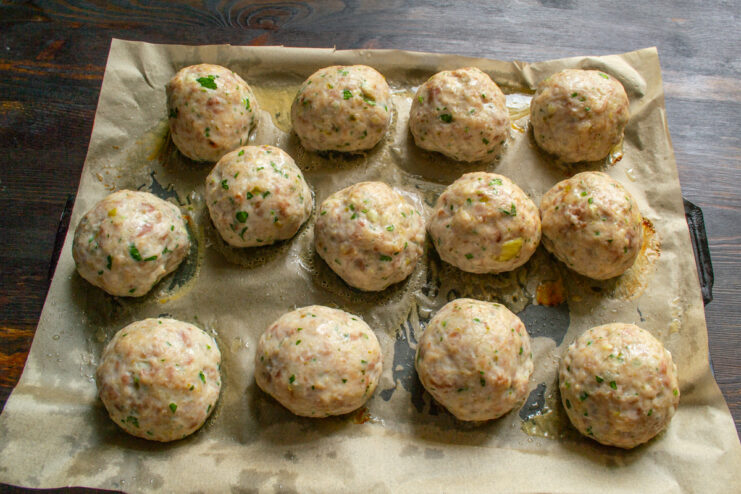 Meatballs After Baking Golden-brown baked meatballs resting on a baking sheet inside the oven.
