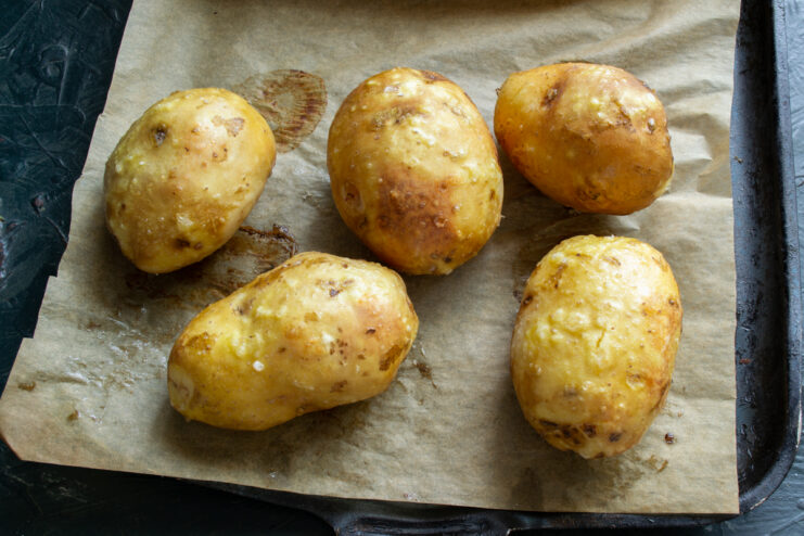 Baking the potatoes Whole baked potatoes on a parchment-lined baking sheet
