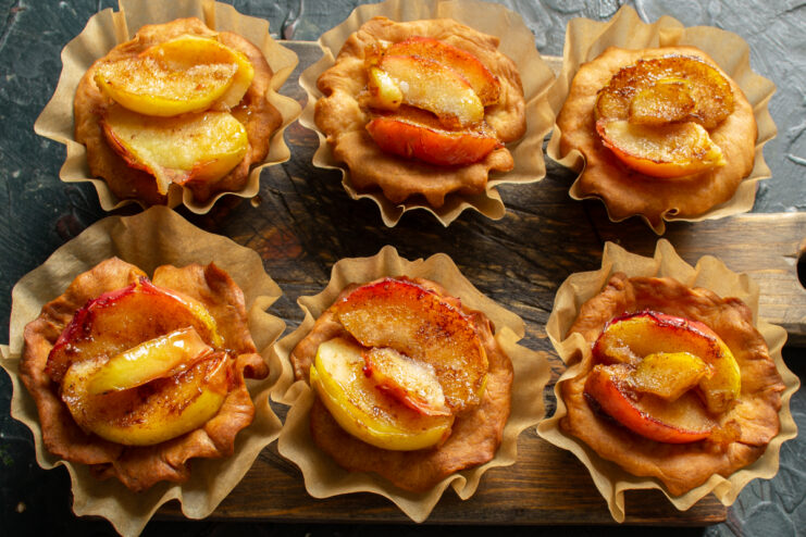 Assembling The Apple Tartlets Sautéed apple slices carefully placed on top of jam in pastry shells
