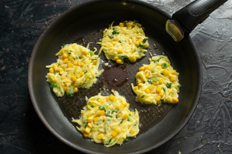 Frying the fritters Frying spoonfuls of potato fritter batter in hot oil